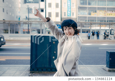 A woman walking in the city with a cup of coffee A woman walking in the city with a cup of coffee 134861114