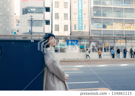 一位女士手捧一杯咖啡走在城市裡。 134861115