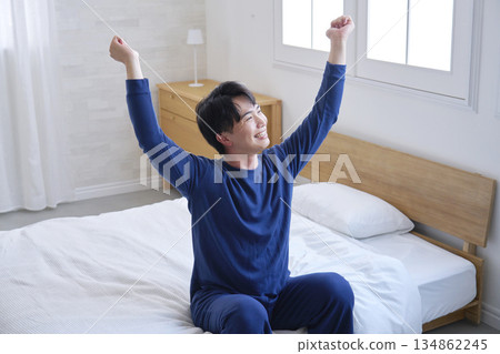 A man in his 20s sitting on the bed and stretching A man in his 20s sitting on the bed and stretching 134862245