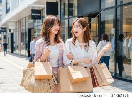 Two young women enjoying shopping. Female friends walking happily while smiling and talking 134862376