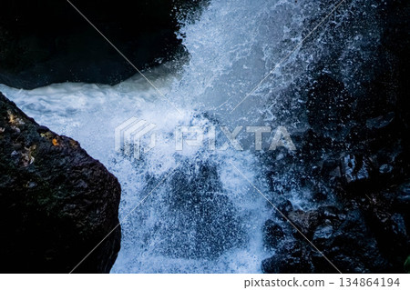 The texture of the waterfall's powerful spray hitting the rocks and the vibrant clear stream 134864194