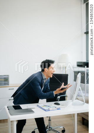 Asian Businessman Analyzing Finance on Tablet and Laptop at modern Office Desk Asian Businessman Analyzing Finance on Tablet and Laptop at modern Office Desk 134865020