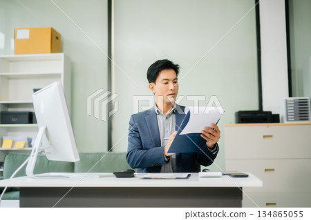 Asian businessman working with working notepad, tablet and laptop documents talking on the smartphone, tablet and laptop 134865055