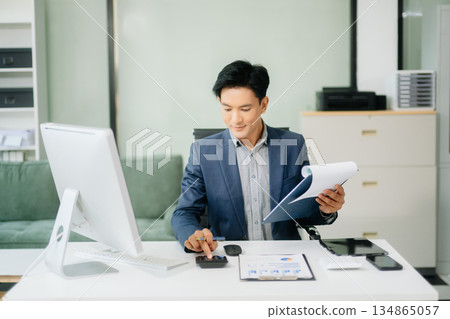 Asian businessman working with working notepad, tablet and laptop documents talking on the smartphone, tablet and laptop Asian businessman working with working notepad, tablet and laptop documents talking on the smartphone, tablet and laptop 134865057