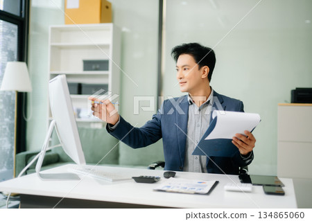 Asian businessman working with working notepad, tablet and laptop documents talking on the smartphone, tablet and laptop 134865060