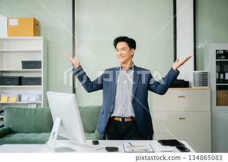 Young attractive Asian male office worker business suits smiling at camera Young attractive Asian male office worker business suits smiling at camera 134865083