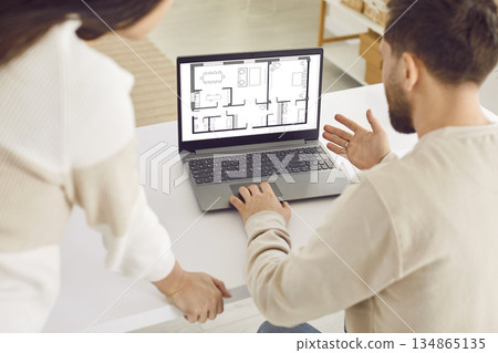 Family couple using laptop computer and looking at house blueprint plan on screen 134865135