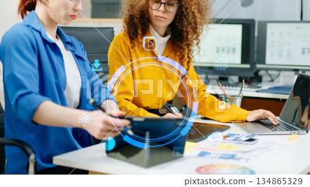 Female designers collaborating on UX UI mobile app planning with wireframes and color palettes in a modern office 134865329