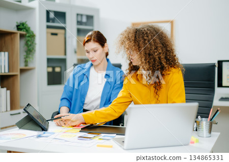 UX UI designers in modern office working on app wireframes, color palettes, and digital tools. Creative teamwork, planning, technology UX UI designers in modern office working on app wireframes, color palettes, and digital tools. Creative teamwork, planning, technology 134865331