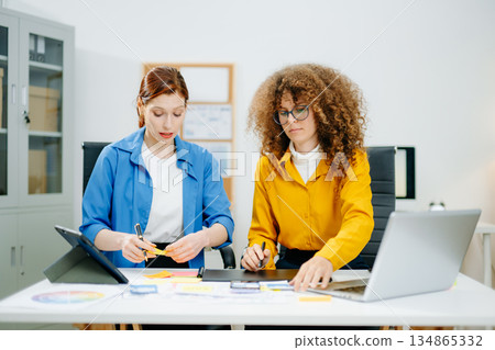 UX UI designers in modern office working on app wireframes, color palettes, and digital tools. Creative teamwork, planning, technology UX UI designers in modern office working on app wireframes, color palettes, and digital tools. Creative teamwork, planning, technology 134865332