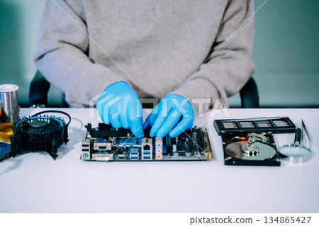 Closeup of expert soldering a green PCB board using precision tools. Ideal for electronics, circuit repair, engineering, tech Closeup of expert soldering a green PCB board using precision tools. Ideal for electronics, circuit repair, engineering, tech 134865427