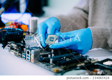 The technician is putting the CPU on the socket of the computer motherboard. electronic engineering electronic repair, electronics measuring and testing, repair 134865428