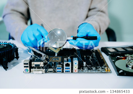 Closeup of technician inspecting CPU with magnifying glass before installing it on motherboard. Concept: repair, upgrade, precision tech work 134865433