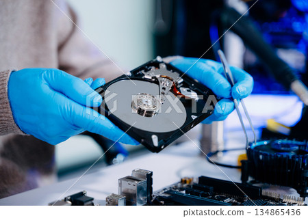 Hard disk drive on the technician's desk and a computer motherboard as a component. the concept of data, hardware, and information technology. 134865436