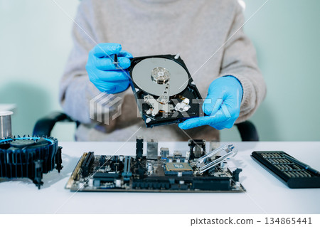 Technician repairing inside of hard disk drive by screwdriver. the concept of data, hardware, technician and technology. computer hardware, repairing, upgrade Technician repairing inside of hard disk drive by screwdriver. the concept of data, hardware, technician and technology. computer hardware, repairing, upgrade 134865441