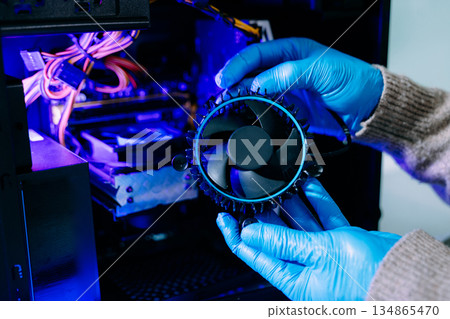 Closeup of technician in gloves holding CPU cooler and heat gun over desktop PC. Ideal image for computer repair, cooling system, and hardware Closeup of technician in gloves holding CPU cooler and heat gun over desktop PC. Ideal image for computer repair, cooling system, and hardware 134865470