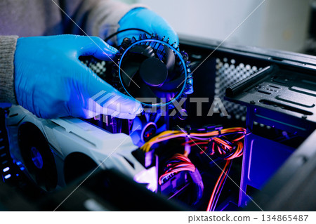 Closeup of technician in gloves holding CPU cooler and heat gun over desktop PC. Ideal image for computer repair, cooling system, and hardware Closeup of technician in gloves holding CPU cooler and heat gun over desktop PC. Ideal image for computer repair, cooling system, and hardware 134865487