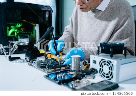Computer technician in gloves safely repairing desktop hardware. Closeup view of hands fixing GPU and motherboard inside open PC case. Perfect for tech 134865506