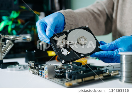 Technician repairing inside of hard disk drive by screwdriver. the concept of data, hardware, technician and technology. computer hardware, repairing, Technician repairing inside of hard disk drive by screwdriver. the concept of data, hardware, technician and technology. computer hardware, repairing, 134865516