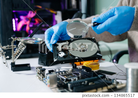 Technician repairing inside of hard disk drive by screwdriver. the concept of data, hardware, technician and technology. computer hardware, repairing, 134865517
