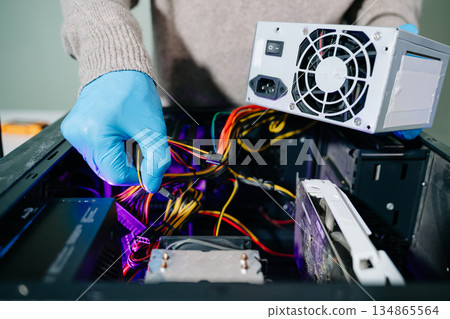 Technician in gloves handling power supply and cables during desktop PC assembly. Perfect for themes like computer repair, PSU install, and hardware build safety. Technician in gloves handling power supply and cables during desktop PC assembly. Perfect for themes like computer repair, PSU install, and hardware build safety. 134865564