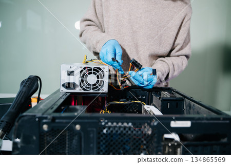Technician in gloves handling power supply and cables during desktop PC assembly. Perfect for themes like computer repair, PSU install, and hardware build safety. Technician in gloves handling power supply and cables during desktop PC assembly. Perfect for themes like computer repair, PSU install, and hardware build safety. 134865569