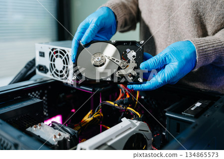 Hard disk drive on the technician's desk and a computer motherboard as a component. the concept of data, hardware, and information technology. 134865573
