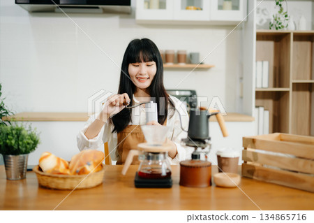 Young female entrepreneur hanging a welcome sign in front of a coffee shop. Beautiful waitress Young female entrepreneur hanging a welcome sign in front of a coffee shop. Beautiful waitress 134865716