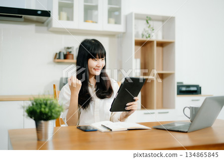 Cheerful businesswoman checking time feeling motivated waiting for leaving office do on their tablet, laptop Cheerful businesswoman checking time feeling motivated waiting for leaving office do on their tablet, laptop 134865845