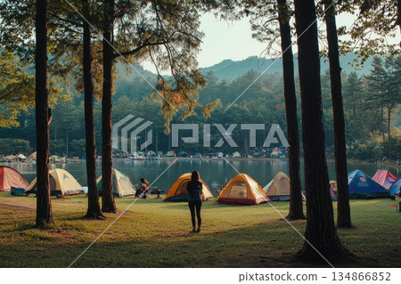 Serene Solo Camper Gazing at Clear Summer Blue Sky by Tranquil Lake Surrounded by Trees Serene Solo Camper Gazing at Clear Summer Blue Sky by Tranquil Lake Surrounded by Trees 134866852