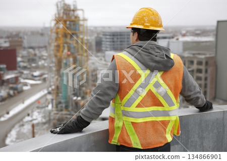 Man in Safety Gear Overlooks Industrial Site with Equipment in Background 134866901