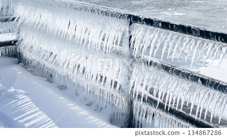 Beautiful Icicles Hanging from a Metal Railing Overlooking a Stunning Frozen Lake Scene Beautiful Icicles Hanging from a Metal Railing Overlooking a Stunning Frozen Lake Scene 134867286