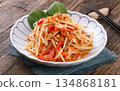 A vibrant and appetizing plate of Thai som tam salad on a rustic wooden table 134868181