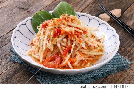 A vibrant and appetizing plate of Thai som tam salad on a rustic wooden table A vibrant and appetizing plate of Thai som tam salad on a rustic wooden table 134868181
