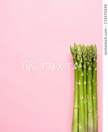 Green asparagus arranged on the right side of a pink background 134870848