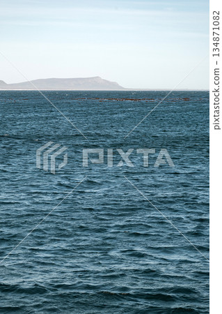 Distant coastline with mountains seen from the deep blue sea Distant coastline with mountains seen from the deep blue sea 134871082