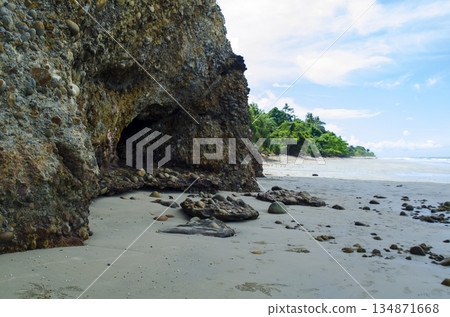 Rugged coastal cliff face meeting shallow turquoise water with bright sky and distant shoreline, Kuala Penyu, Sabah, Malaysia. Rugged coastal cliff face meeting shallow turquoise water with bright sky and distant shoreline, Kuala Penyu, Sabah, Malaysia. 134871668