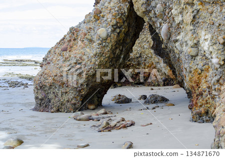 Natural rock arch on the beach with textured stone, shallow water, and airy sky, Kuala Penyu, Sabah, Malaysia. Natural rock arch on the beach with textured stone, shallow water, and airy sky, Kuala Penyu, Sabah, Malaysia. 134871670