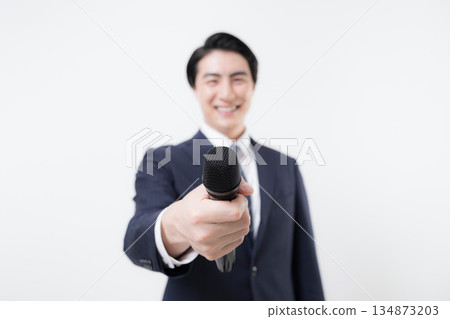 A businessman holding a microphone and encouraging an interview, such as a presenter or reporter, close-up of a microphone without a face A businessman holding a microphone and encouraging an interview, such as a presenter or reporter, close-up of a microphone without a face 134873203