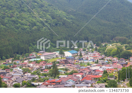Aerial view of a rural Japanese village surrounded by lush green mountains Aerial view of a rural Japanese village surrounded by lush green mountains 134873730
