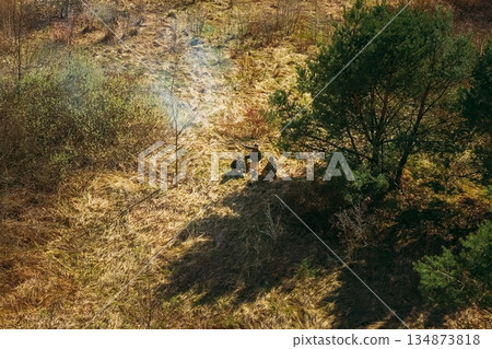 Men Dressed As US American Soldiers Of USA Infantry Of World War II open fire shooting mortar In spring Autumn Day. Soldiers shots mortar during battle In dry grass. Aerial view elevated shot Men Dressed As US American Soldiers Of USA Infantry Of World War II open fire shooting mortar In spring Autumn Day. Soldiers shots mortar during battle In dry grass. Aerial view elevated shot 134873818