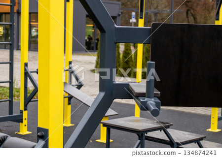 Fitness equipment is set up in a public area with workout stations and open spaces for exercise activities in daylight Fitness equipment is set up in a public area with workout stations and open spaces for exercise activities in daylight 134874241