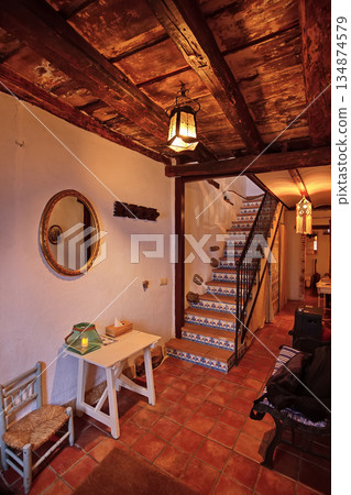 Cozy rustic interior with wooden beams, staircase and lantern lighting in a quaint home Cozy rustic interior with wooden beams, staircase and lantern lighting in a quaint home 134874579