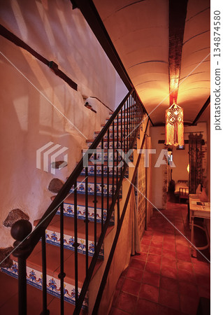 Cozy rustic living space with decorative tiled staircase and warm hanging lantern lighting 134874580