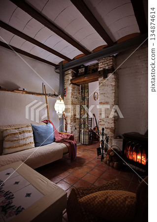 Cozy rustic living room with fireplace, warm lighting, and comfortable seating for a homely scene 134874614