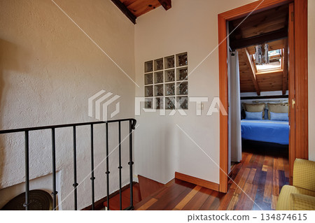 Cozy loft hallway leading to a bright bedroom with skylight and glass block wall 134874615