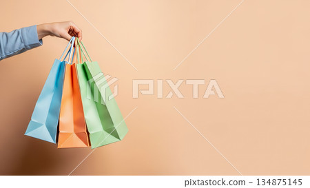 Hand holding colorful paper shopping bags on pastel background retail sale consumer concept Hand holding colorful paper shopping bags on pastel background retail sale consumer concept 134875145