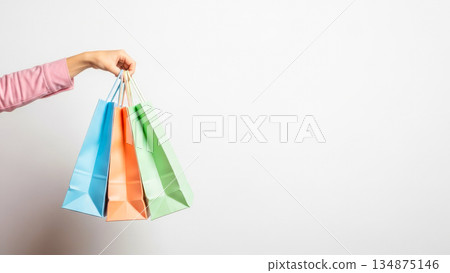 Hand holding colorful paper shopping bags isolated on white background retail sale consumer marketing concept Hand holding colorful paper shopping bags isolated on white background retail sale consumer marketing concept 134875146