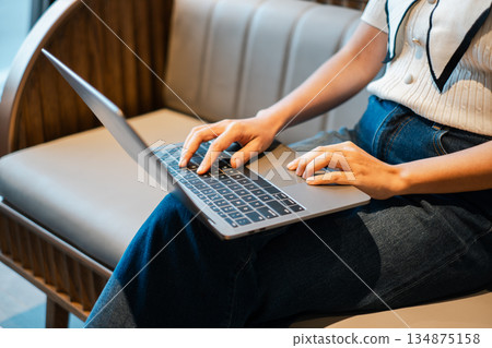 Close-up of a woman using a laptop on a wooden bench, showcasing modern technology and casual fashion. Close-up of a woman using a laptop on a wooden bench, showcasing modern technology and casual fashion. 134875158