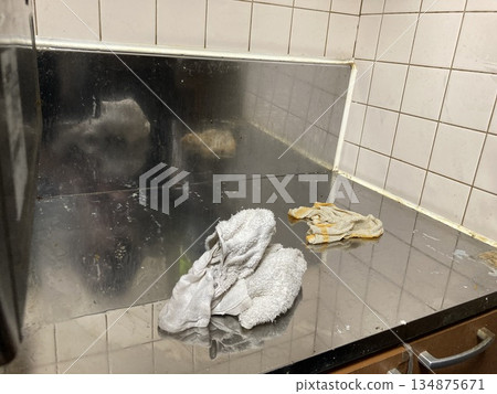 A kitchen scene where a stainless steel countertop is wiped clean with a cloth A kitchen scene where a stainless steel countertop is wiped clean with a cloth 134875671